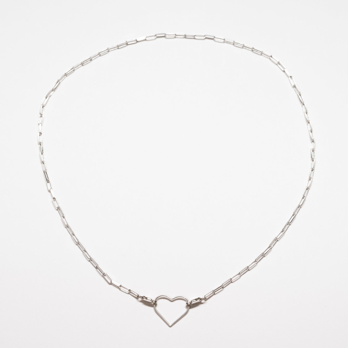 Silver necklace with a heart-shaped clasp on a light gray background
