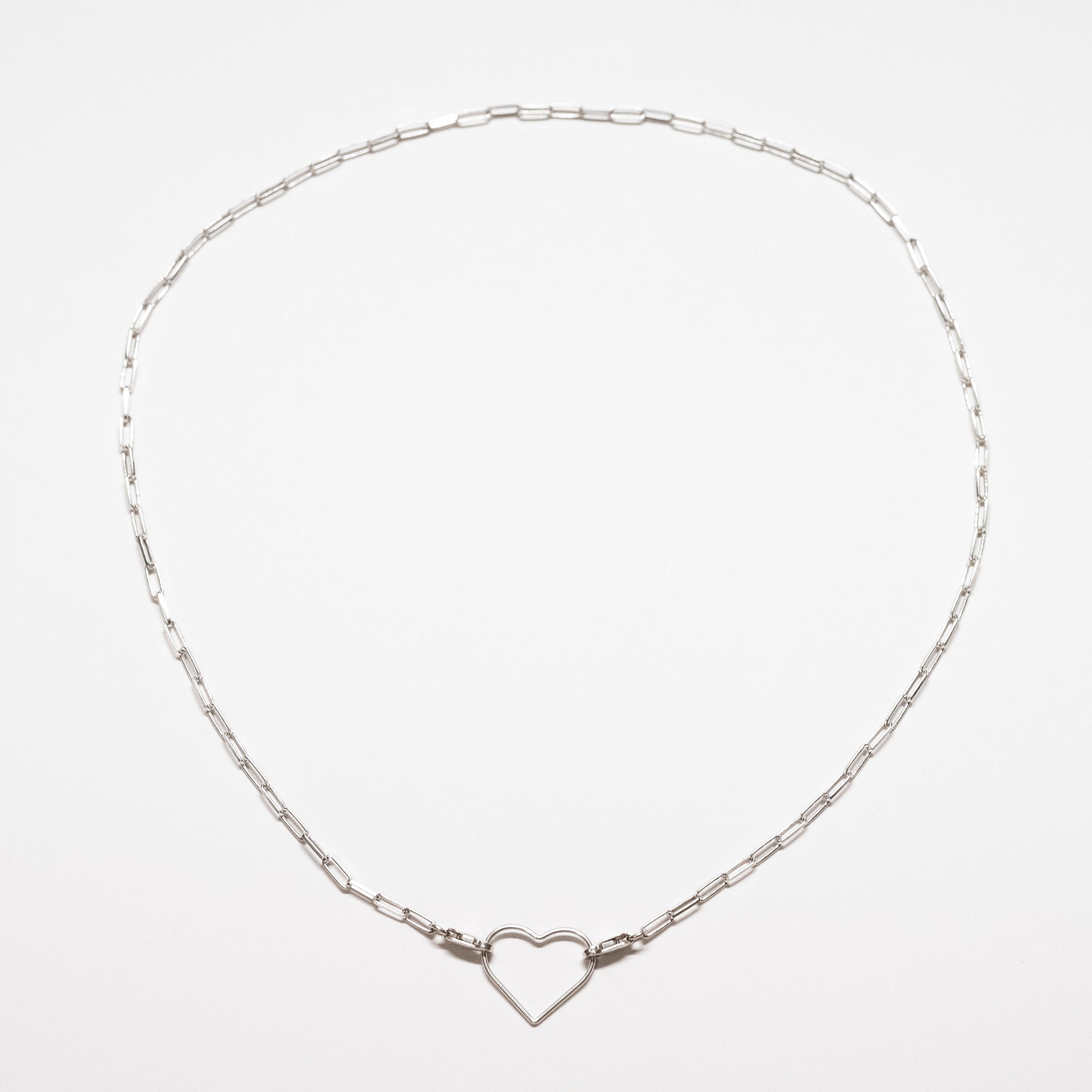 Silver necklace with a heart-shaped clasp on a light gray background